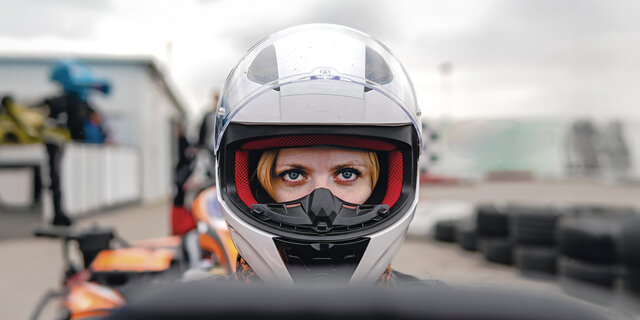 Frau mit weißem Sturzhelm im Cockpit