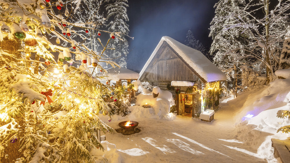 Schneebedeckte Holzhütte und Bäume, die mit Weihnachtskugeln geschmückt sind.