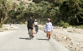 Zwei Radfahrer fahren einem Einheimischen im Oman entgegen.