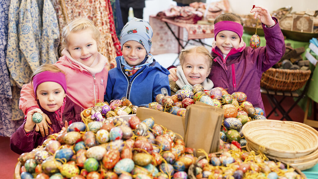 5 Kinder stehen hinter einer großen Schüssel mit bemalten Ostereiern am Osterhof von Schloss Hof.