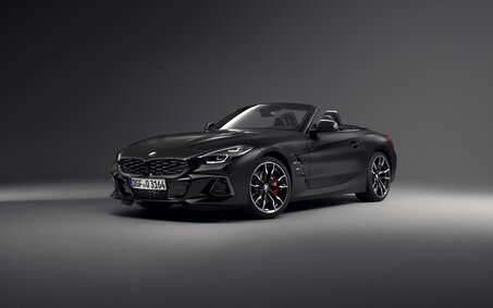 Ein mattschwarzes BMW Z4 Cabrio steht in einem dunklen Studio, von schräg vorne