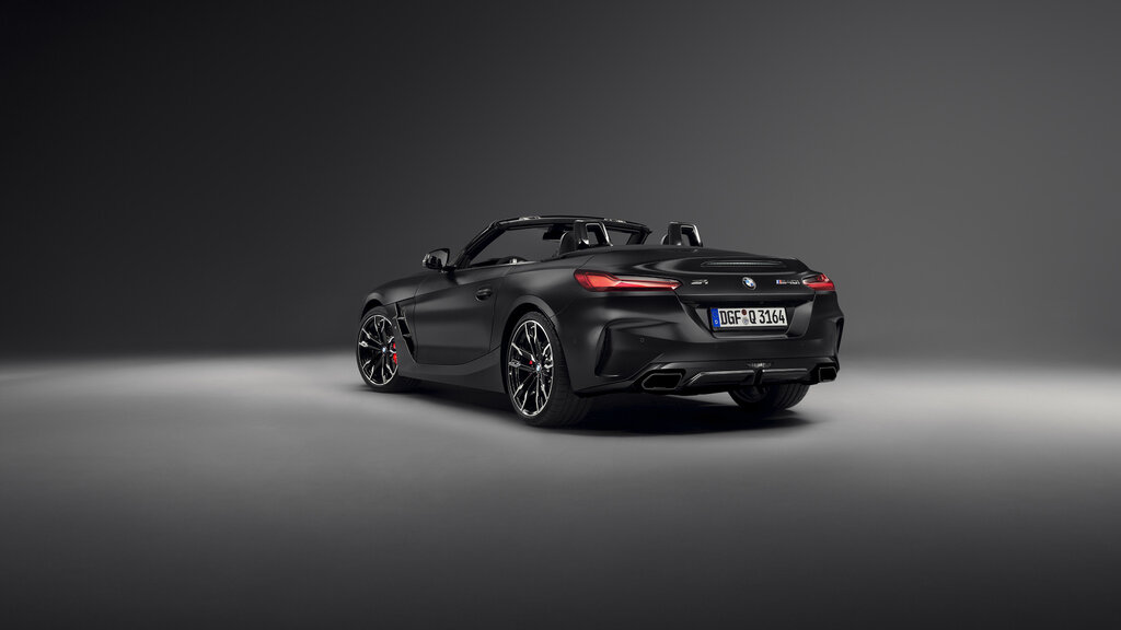 Ein mattschwarzes BMW Z4 Cabrio steht in einem dunklen Studio, von schräg hinten