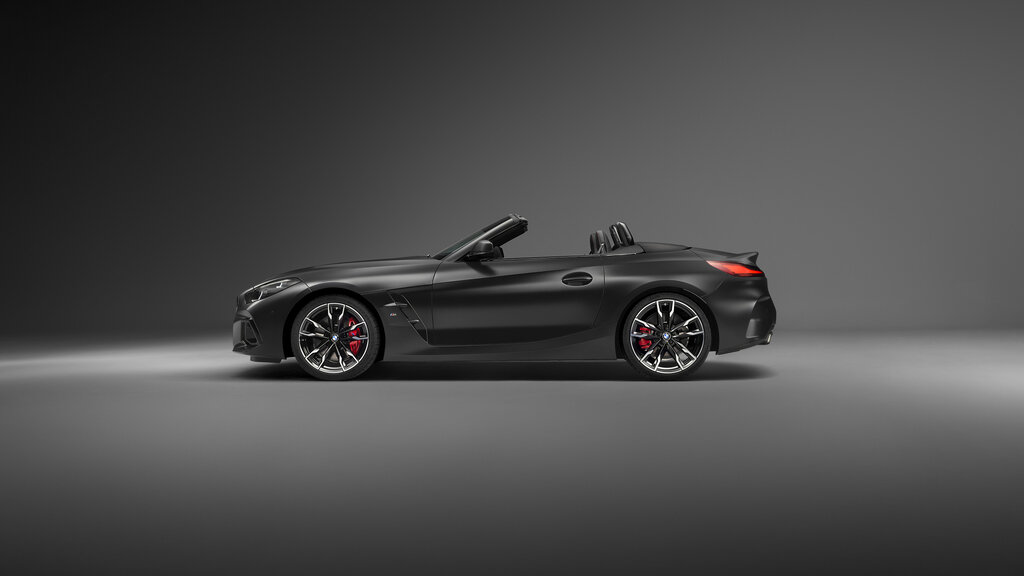 Ein mattschwarzes BMW Z4 Cabrio steht in einem dunklen Studio, seitlich