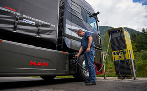 Ein Mann steckt einen Lkw an einer Ladesäule an