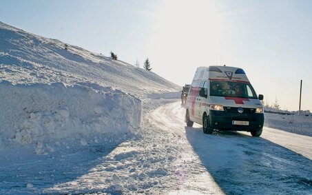 Ein Rettungswagen des österreichischen Roten Kreuz in winterlicher Landschaft.