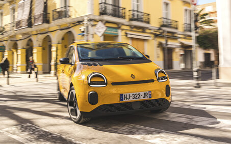 Ein gelber Renault Twingo fährt um eine Kurve in der Stadt.