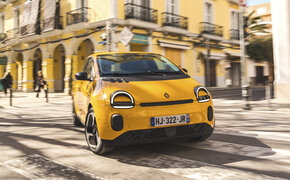 Ein gelber Renault Twingo fährt um eine Kurve in der Stadt.