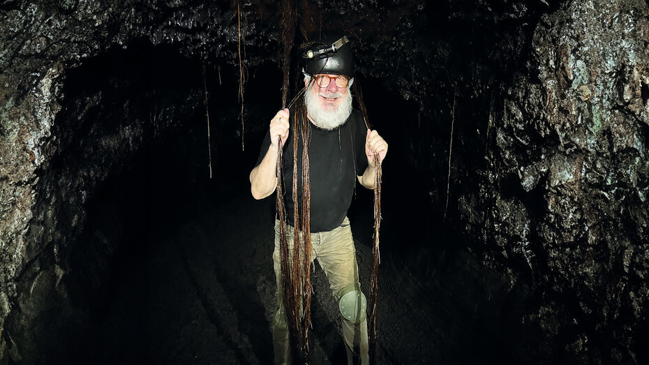 Mann mit Bart und Helm steht in einer dunklen Höhle