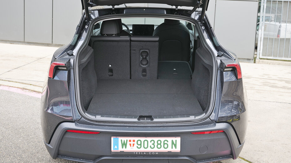 Kofferraum eines dunkelgrauen Tesla Model Y mit umgelegtem rechten Sitz.