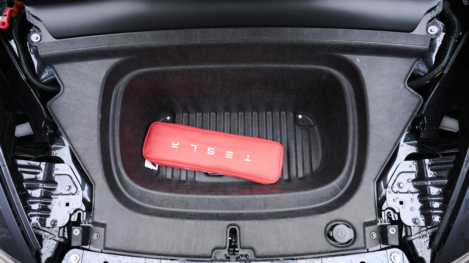 Frunk eines Tesla Model Y, in dem sich eine rote Verpackung mit Tesla-Schriftzug befindet.