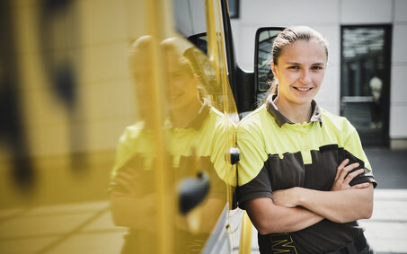 Pannenhelferin Lenie Tieber steht mit verschränkten Händen neben einem großen gelben Fahrzeug.
