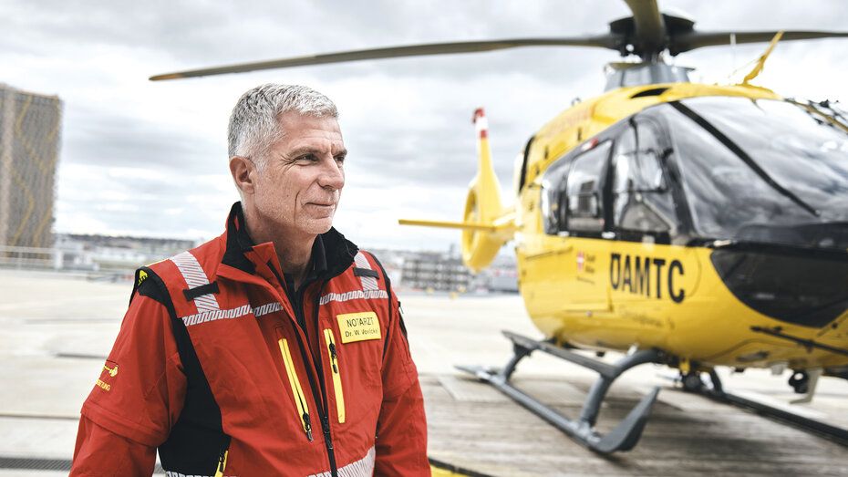 Dr. Wolfgang Voelckel, Ärztlicher Leiter der ÖAMTC Flugrettung. Neben ihm ist ein Christophorus Hubschrauber zu sehen. 