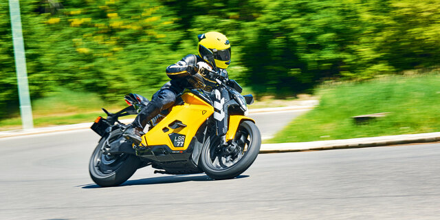 Gelbes Motorrad fährt in Schräglage um Kurve