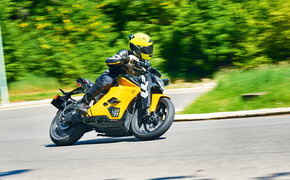 Gelbes Motorrad fährt in Schräglage um Kurve