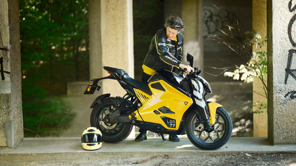 Fahrer stellt das gelb-schwarze Motorrad auf dem Seitenständer ab. 