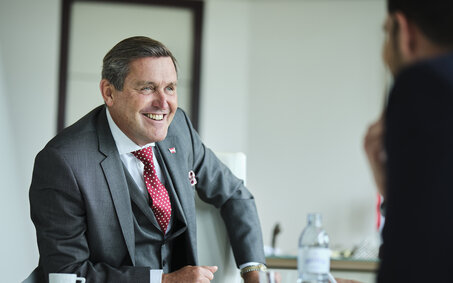 Portrait von Verkehrsminister Peter Hanke lachend im Interview.