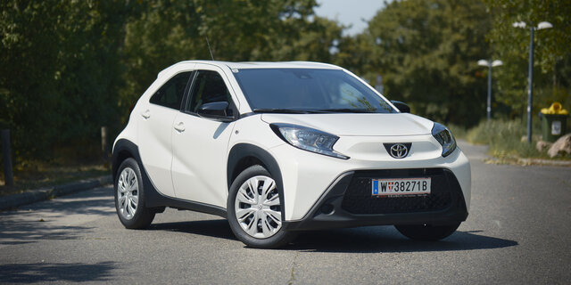 Ein weißer Toyota Kleinwagen steht auf einer Straße