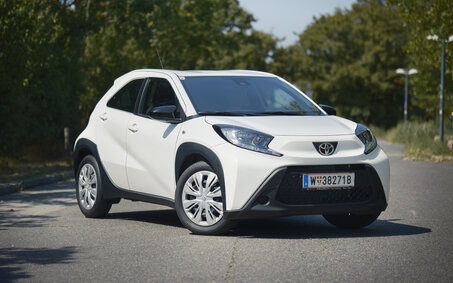 Ein weißer Toyota Kleinwagen steht auf einer Straße