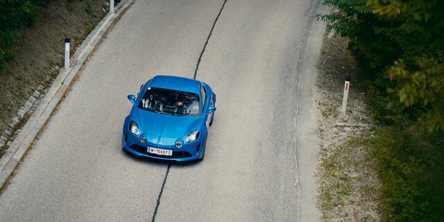 Eine blaue Alpine A110 fährt auf der Höhenstraße, von oben fotografiert