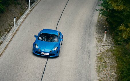 Eine blaue Alpine A110 fährt auf der Höhenstraße, von oben fotografiert