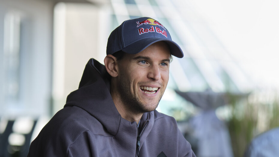 Der Ex-Tennisspieler Dominic Thiem mit Red-Bull-Kappe und Kapuzenpullover lacht während eines Gespräches.