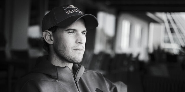 Schwarz-weiß-Foto des Ex-Tennisspielers Dominic Thiem, wie er in die Ferne blickt.