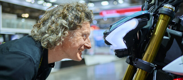 Mann blickt direkt in Motorrad-Scheinwerfer.