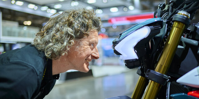 Mann blickt direkt in Motorrad-Scheinwerfer.