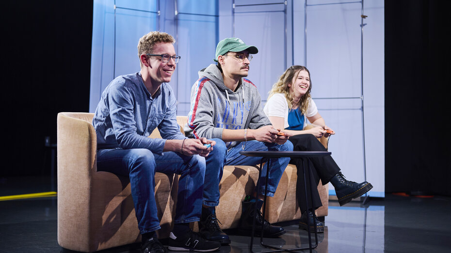 Drei Redakteure spielen gemeinsam, sie lachen.