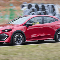 Ein roter Renault Clio fährt an einer Wand mit Graffiti vorbei