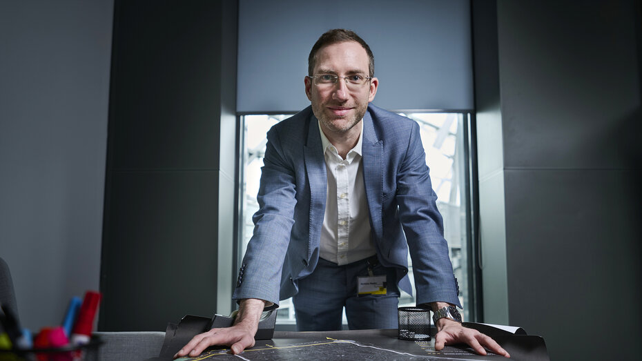 Verkehrsexperte Matthias Nagler im Anzug, kurze braune Haare und Brille, lehnt sich mit beiden Händen auf einen Tisch.