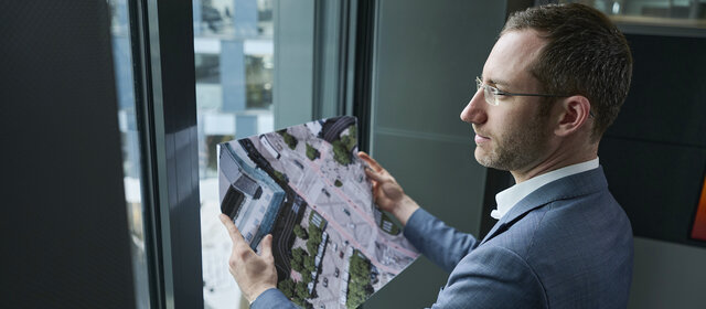 Verkehrsexperte Matthias Nagler steht vor einem Fenster und hält eine Karte in der Hand.