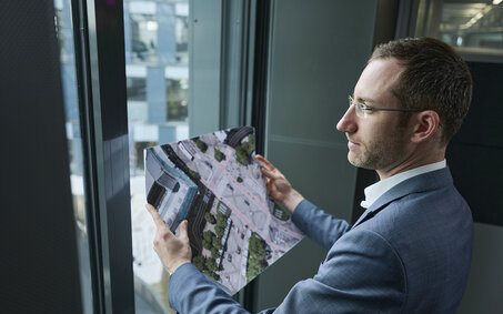 Verkehrsexperte Matthias Nagler steht vor einem Fenster und hält eine Karte in der Hand.
