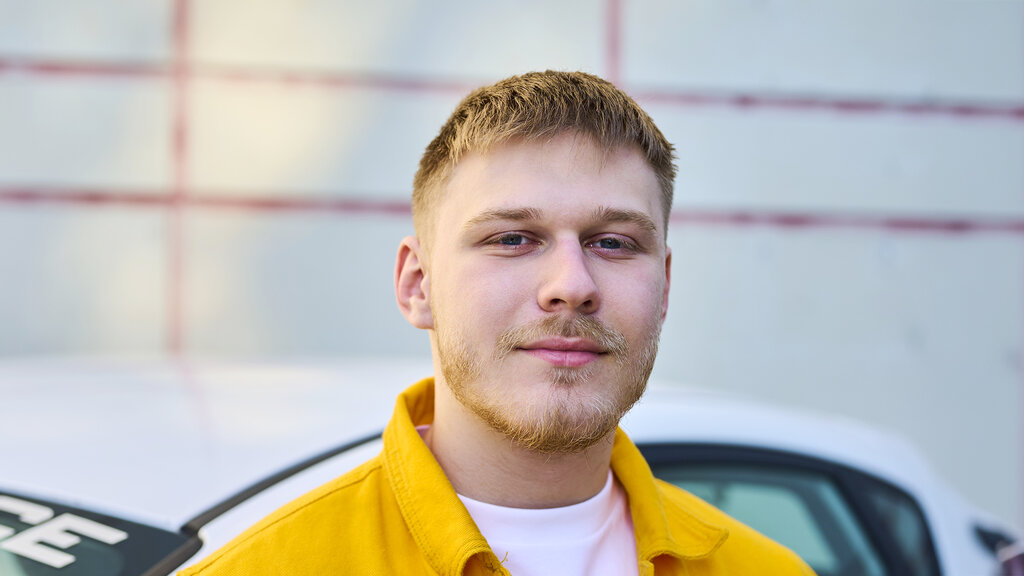 Portraitbild von Paul. Er ist blond und hat eine gelbe Jacke an.