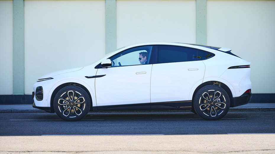 Ein weißer Xpeng G6 steht längs auf der Straße vor einer leicht grünen Wand.