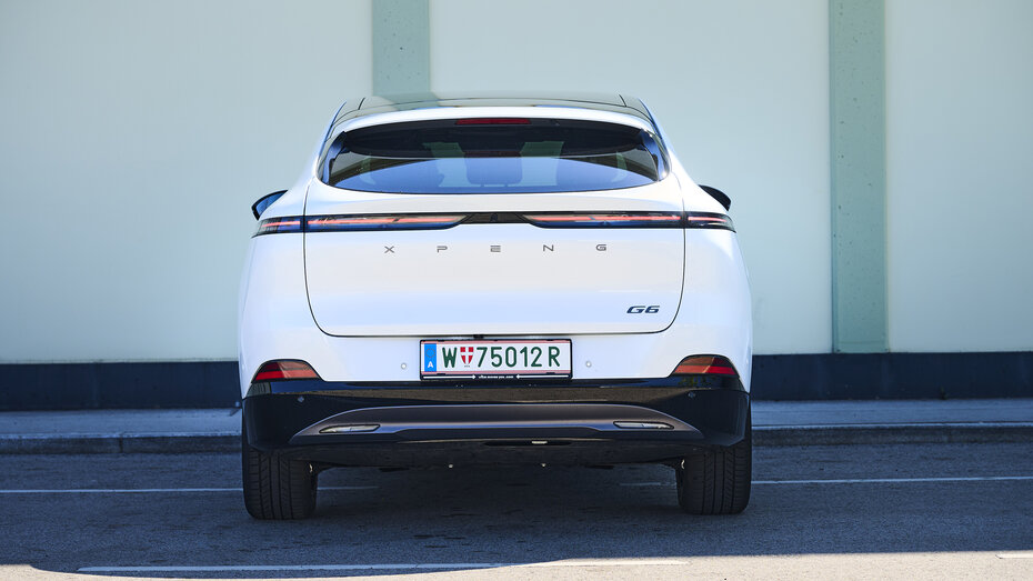 Heck eines weißen Xpeng G6, der vor einer leicht grünen Wand steht.