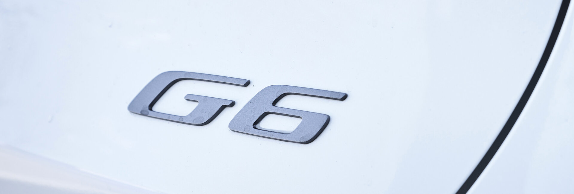 G6-Schriftzug in Chrom am Heck eines weißen Xpeng G6.