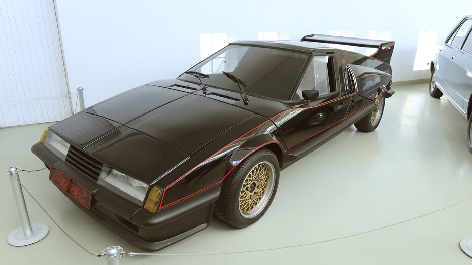 Ein futuristisch aussehendes, flaches schwarzes Sportauto mit Heckspoiler.