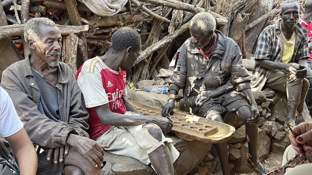 Afrikanische Männer spielen ein Holzspiel.