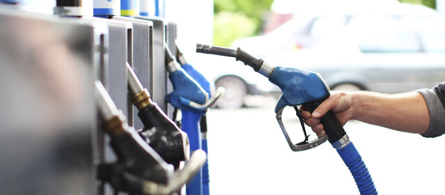 Eine Hand nimmt den Tankstutzen in die Hand an einer Tankstelle.
