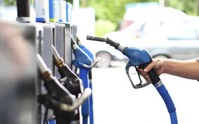 Eine Hand nimmt den Tankstutzen in die Hand an einer Tankstelle.