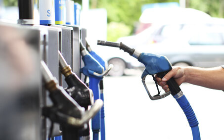 Eine Hand nimmt den Tankstutzen in die Hand an einer Tankstelle.