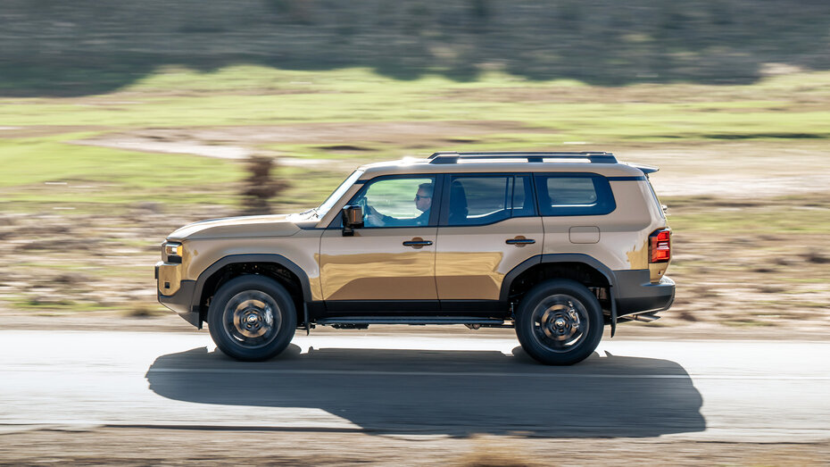 Ein braunes Geländeauto fährt auf einer Landstraße.