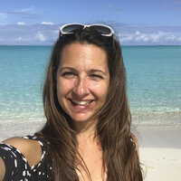 Eine Frau mit langen Haaren steht am Strand und macht ein Selfie.