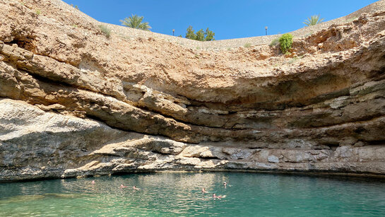 Urlauber baden in einem natürlichen Pool umringt von Felsen.