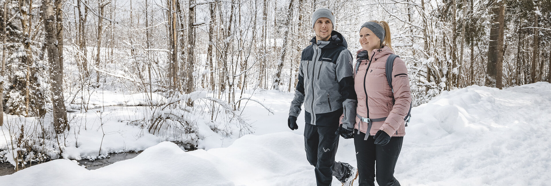 Ein Paar geht durch den verschneiten Wald.
