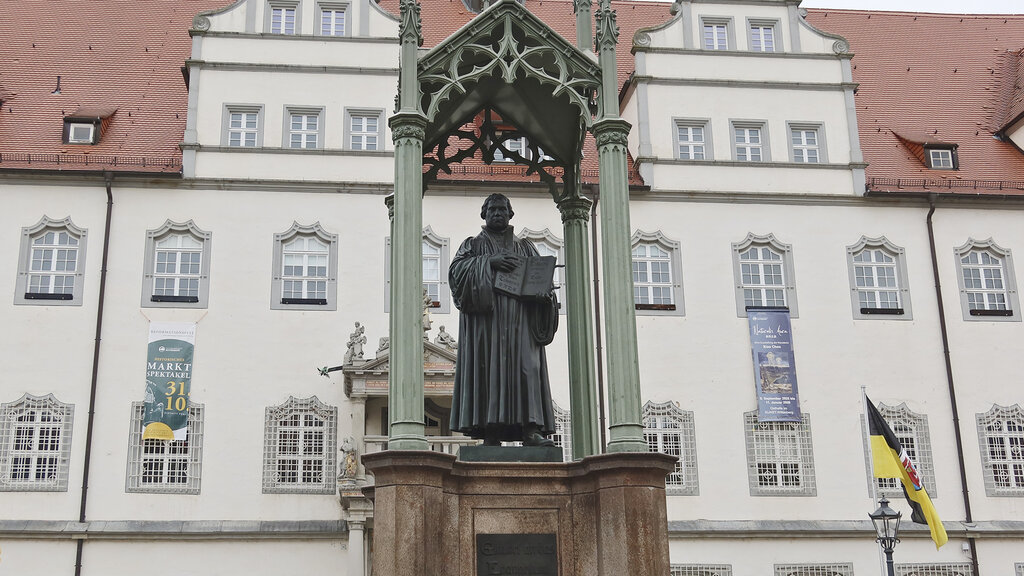 Ein Denkmal unter einem gusseisernen Baldachin, Luther hält eine aufgeschlagene Bibel.