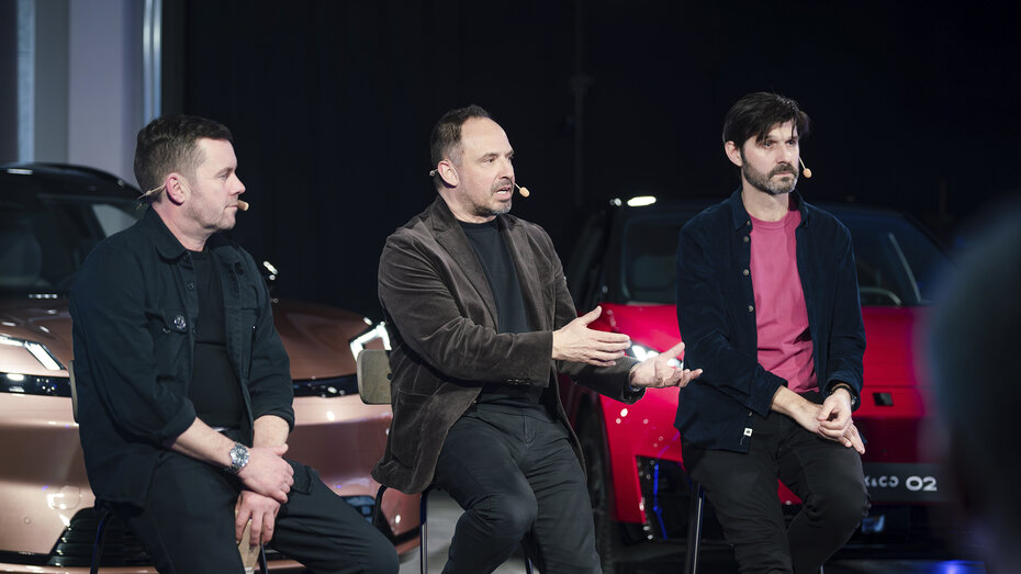 Drei Personen sitzen bei einem Q&A auf Hockern vor drei Fahrzeugen.