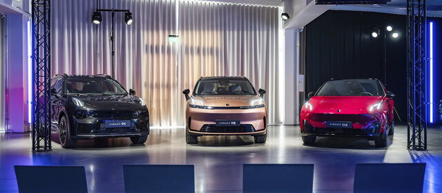 Drei Fahrzeuge der Marke Lynk & Co stehen auf einer Bühne im Scheinwerferlicht.