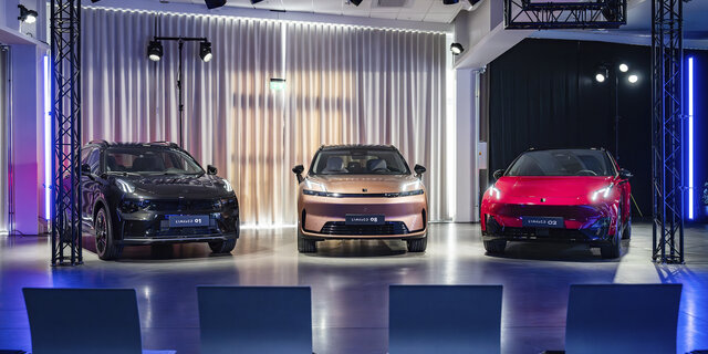 Drei Fahrzeuge der Marke Lynk & Co stehen auf einer Bühne im Scheinwerferlicht.